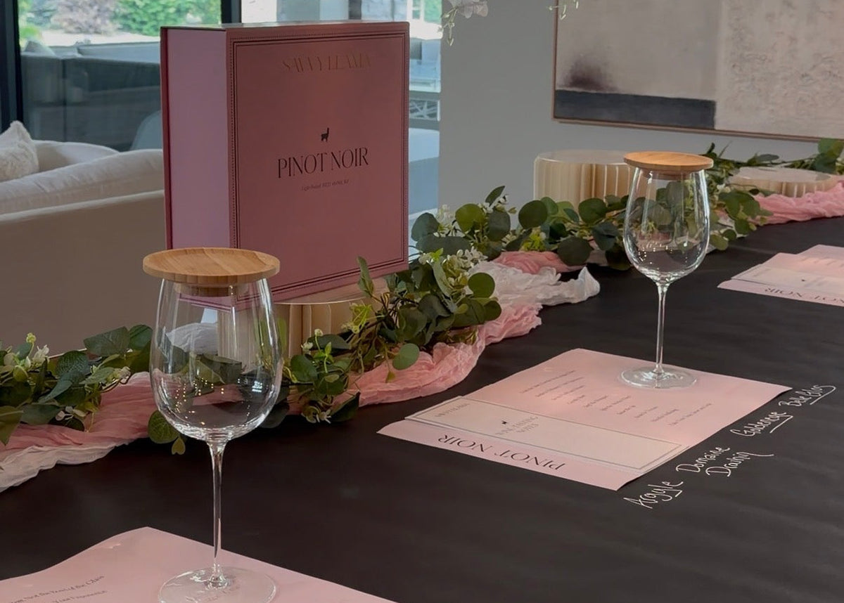 Savvy Llama Pinot Noir Party Kit atop a black table with chalk for wine tasting event.