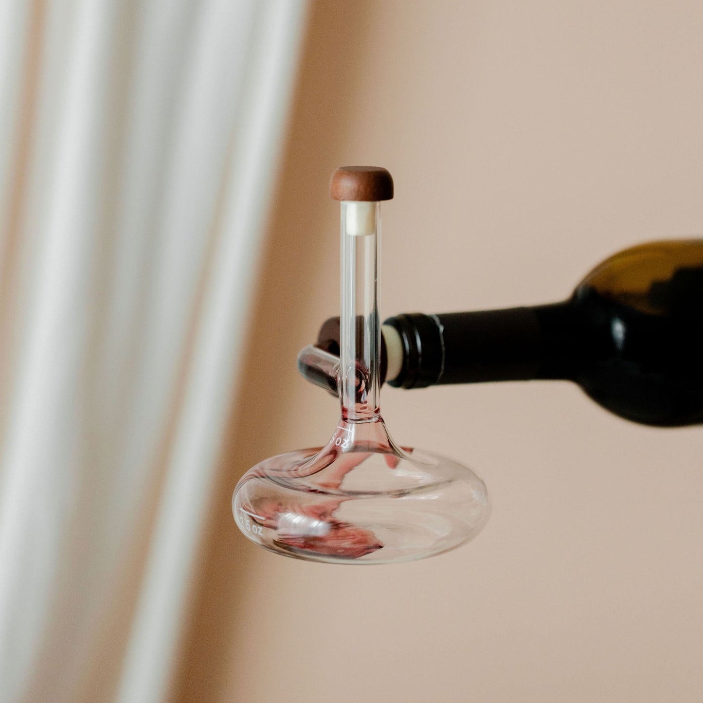 Savvy Llama on-the-bottle decanter aerating red wine on a soft cream studio background