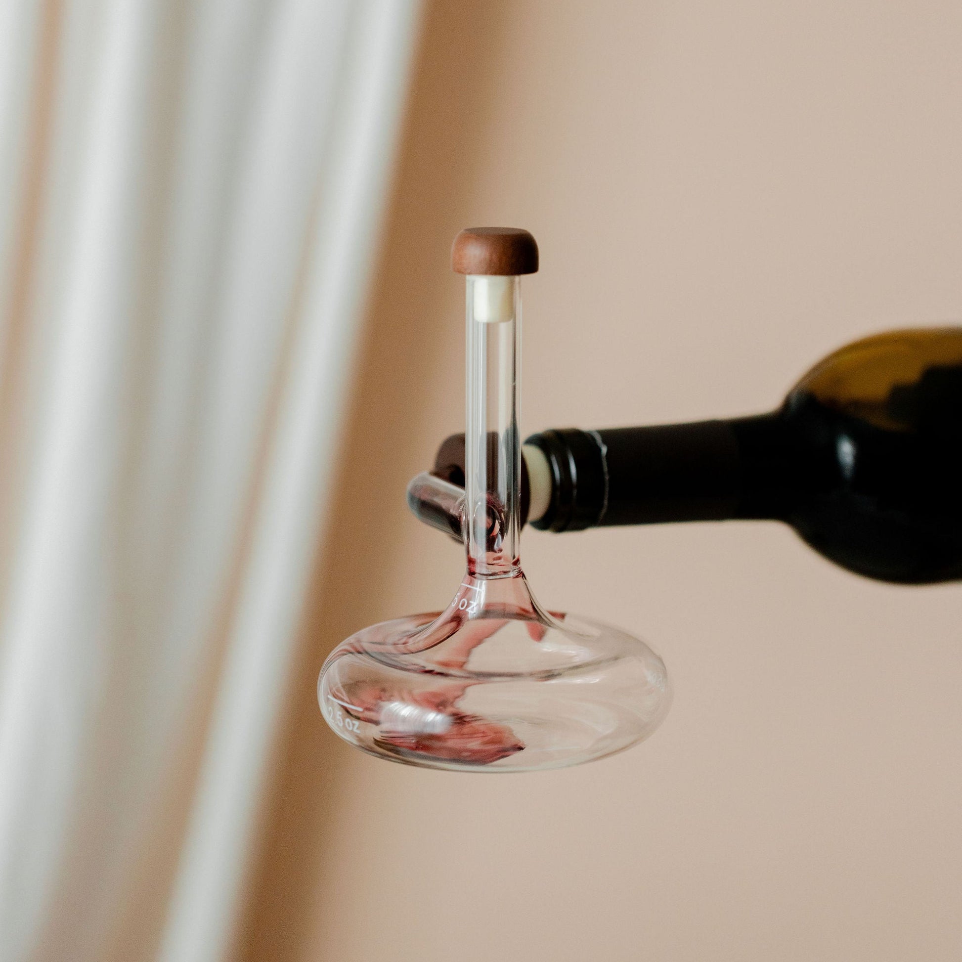 Savvy Llama on-the-bottle decanter aerating red wine on a soft cream studio background